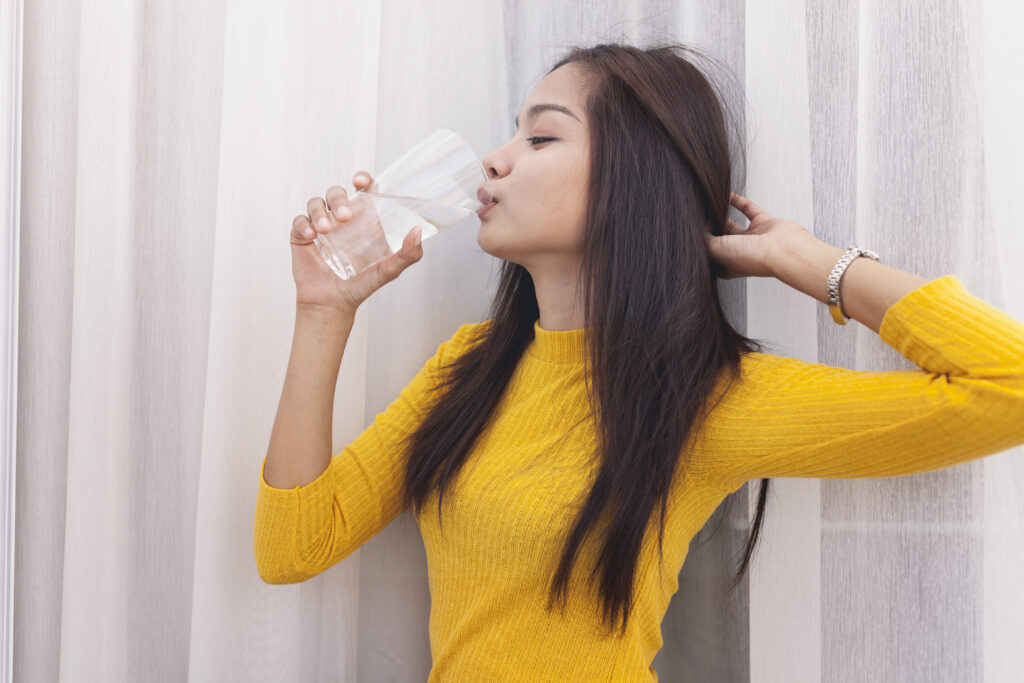 girl drinking water touching her hair